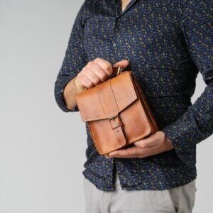 δερμάτινο ανδρικό τσαντάκι με αποσπώμενο λουρί για χιαστί κράτημα διαθέτει επίσης και χεράκια στην πάνω μεριά. ταμπά χρώμα